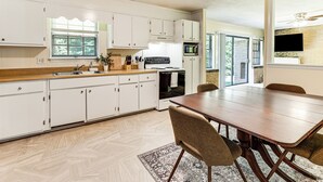 Une cuisine moderne avec des meubles blancs, un plan de travail en bois et une table à manger avec des chaises.