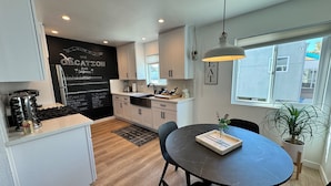 A modern kitchen with white cabinets, a black backsplash, and a dining area with a round table and chairs.