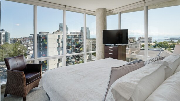 Une chambre d’hôtel moderne avec un grand lit, une télévision et une vue sur la ville.