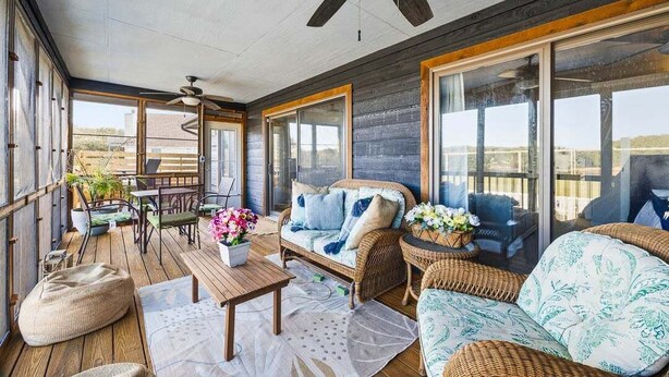 A spacious balcony with wicker furniture, a ceiling fan, and large windows offering a view of the landscape. - Salty Bunker | 5200 ft to the beach | Private Pool (Kitty Hawk)