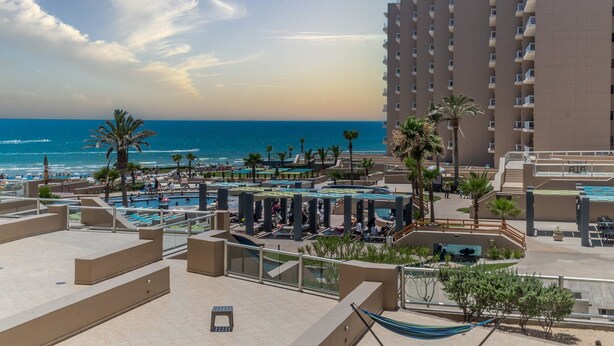 Un complex turístic amb diverses piscines, palmeres i vista a l'oceà.
