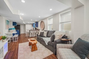 A modern living room with a grey sofa, a wooden coffee table, and a kitchen in the background. - 3BR/2BA Unit Just Furnished (Ventnor City)