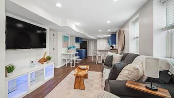 A modern living room with a flat-screen TV, a wooden coffee table, and a sofa.