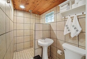 A bathroom with a wooden ceiling, beige tiles, a sink, a toilet, and towels with starfish designs. - 3BR/2BA Unit Just Furnished (Ventnor City)