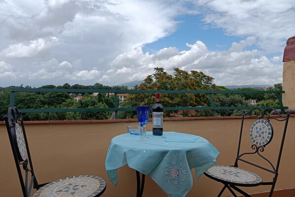 Un balcon avec une table et des chaises, une bouteille de vin et un verre.