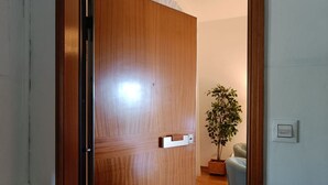 Una porta de fusta amb una manilla i una petita estant, una planta en test i un interruptor de llum a la paret.