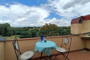 Une terrasse avec une table et des chaises, une bouteille de vin et une vue sur le paysage environnant.