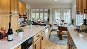 A modern kitchen with wooden cabinets, a dishwasher, and a dining area with a table and chairs.
