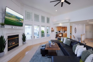 A spacious living room with a fireplace, a large flat-screen TV, a black leather sofa, and a dining area in the background. - A HOT-AIR-BALLOON-THEMED 5-BEDROOM ESCAPE FOR YOUR WHOLE CREW IN WALLA WALLA ... (College Place)