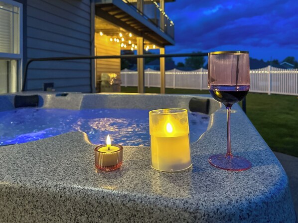 Un jacuzzi con una vela y una copa de vino sobre una superficie de piedra.