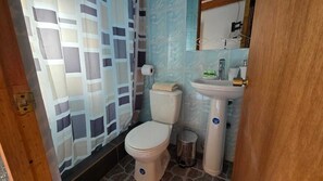 A bathroom with a toilet, sink, and shower curtain. - Hostal Pablito (San Pedro de Atacama)
