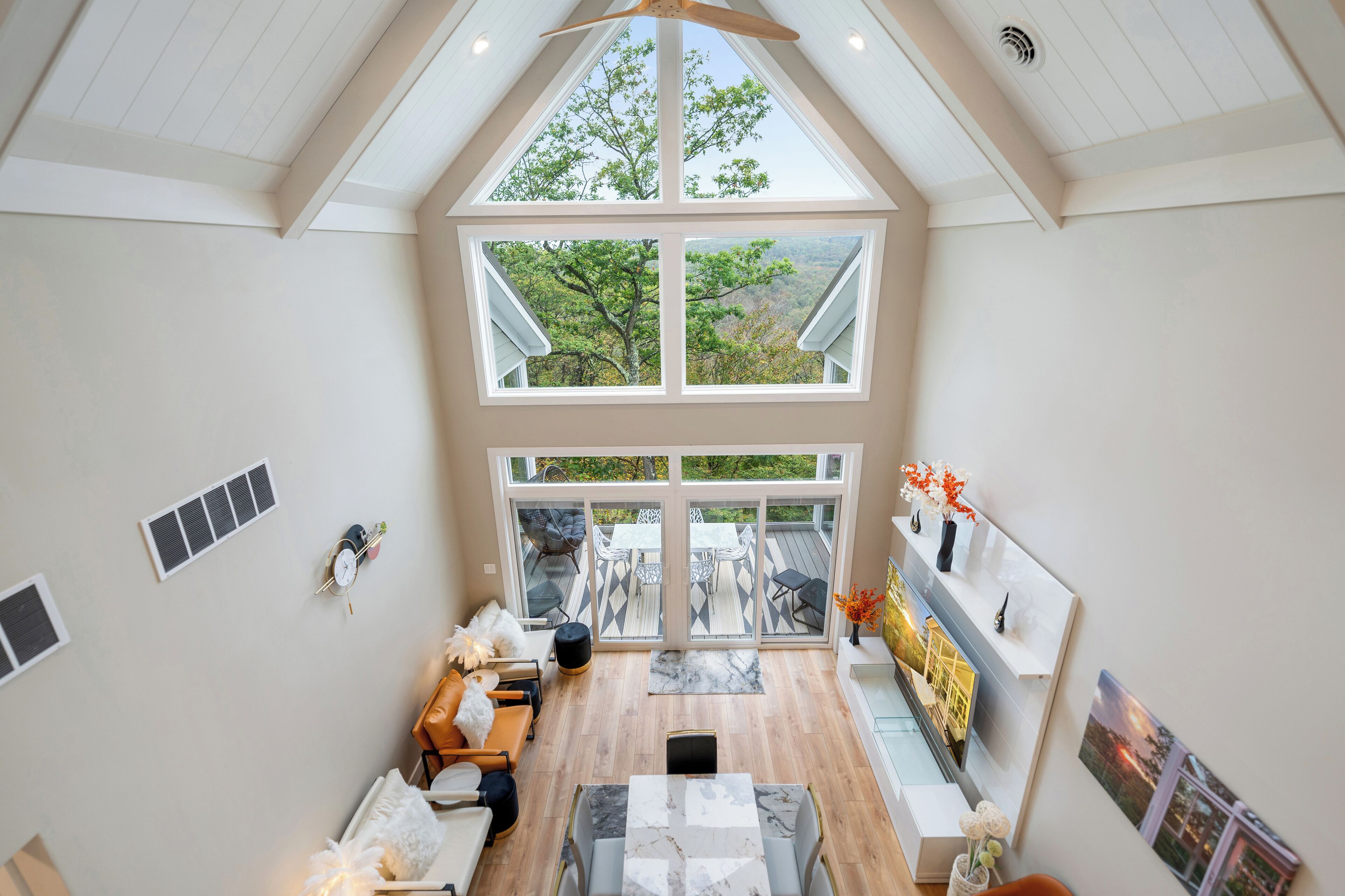 Un intérieur spacieux avec un plafond haut, de grandes fenêtres, un coin repas et une vue sur l’extérieur.