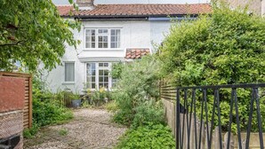 A house with a gravel pathway leading to the front door, surrounded by greenery and a black metal gate. - Angel Cottage, Wenhaston. Nr Southwold and Minsmere (Suffolk)