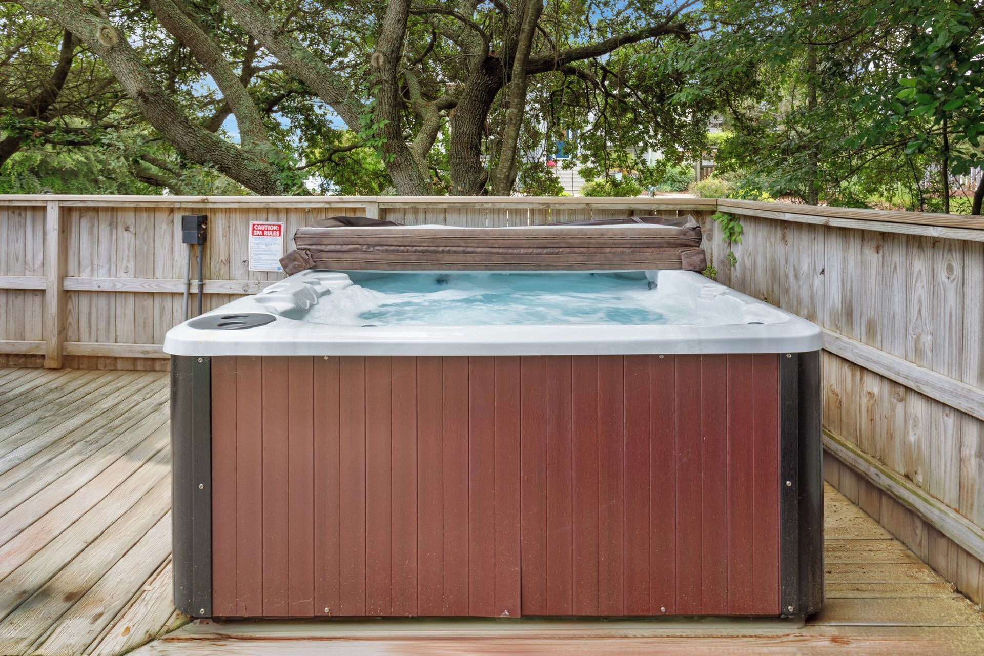 A hot tub in a wooden deck area surrounded by trees.