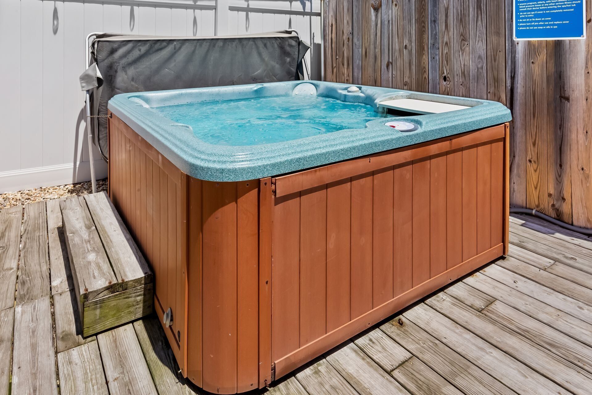 Un bain à remous en bois, doté d ’un couvercle, une terrasse en bois et une clôture en bois en arrière-plan.