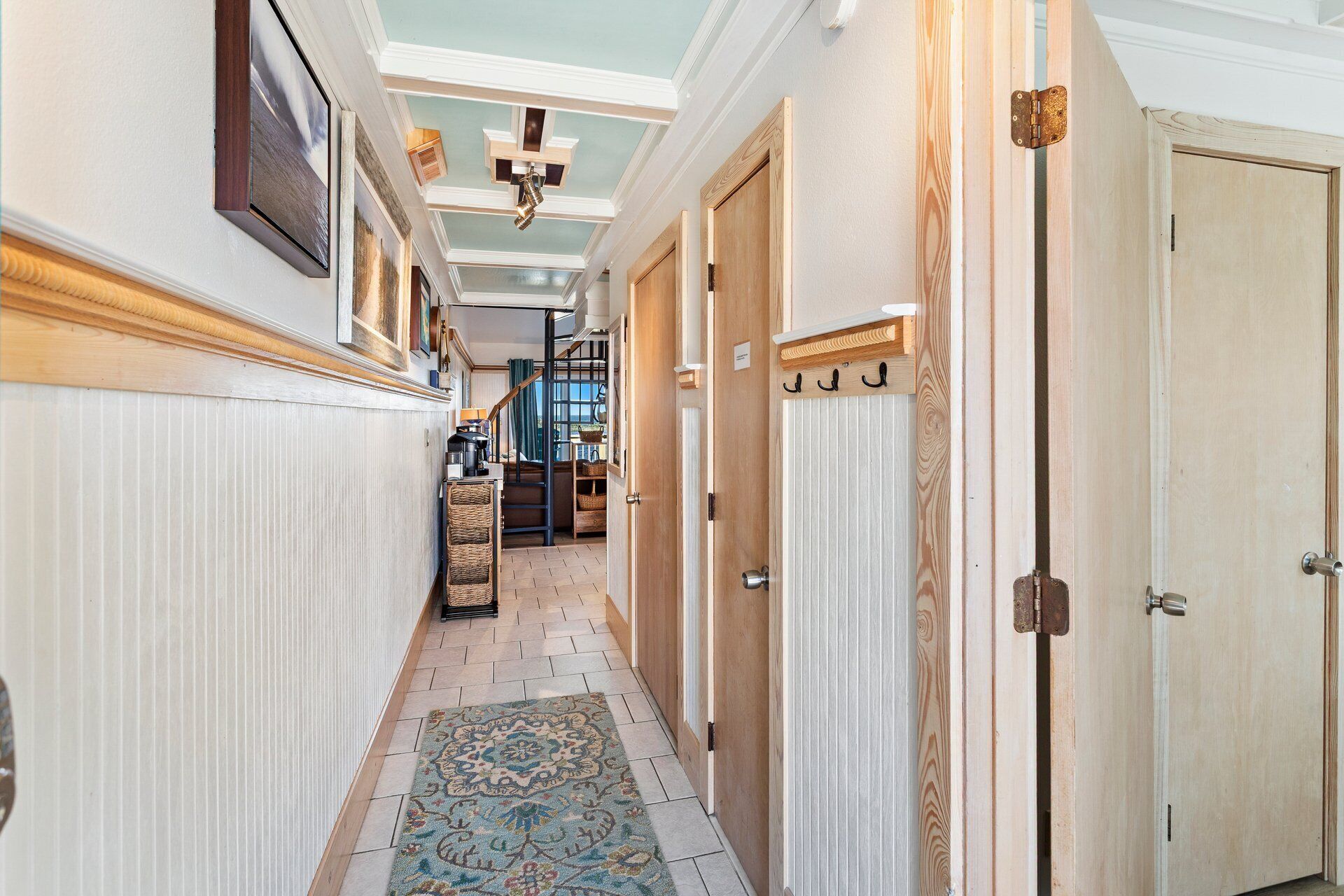Un couloir avec des portes en bois, un tapis à motifs et un plafond doté de lucarnes.