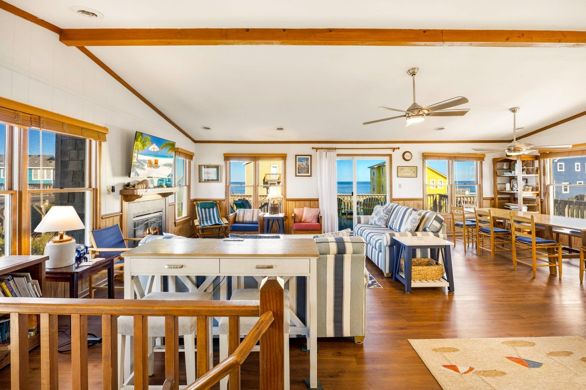 A spacious living area with a fireplace, seating, and a view of the ocean.