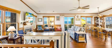 A spacious living area with a fireplace, seating, and a view of the ocean.