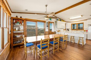 Une cuisine spacieuse dotée d’un grand îlot central, de planchers en bois et d’un ventilateur de plafond.