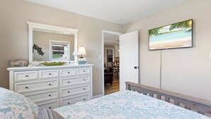 Ein Schlafzimmer mit Bett, Kommode und Fernseher an der Wand.
