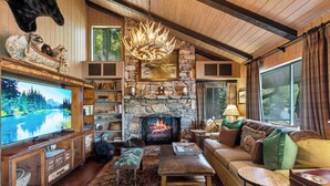 A cozy living room with a stone fireplace, a television, and a comfortable seating area.