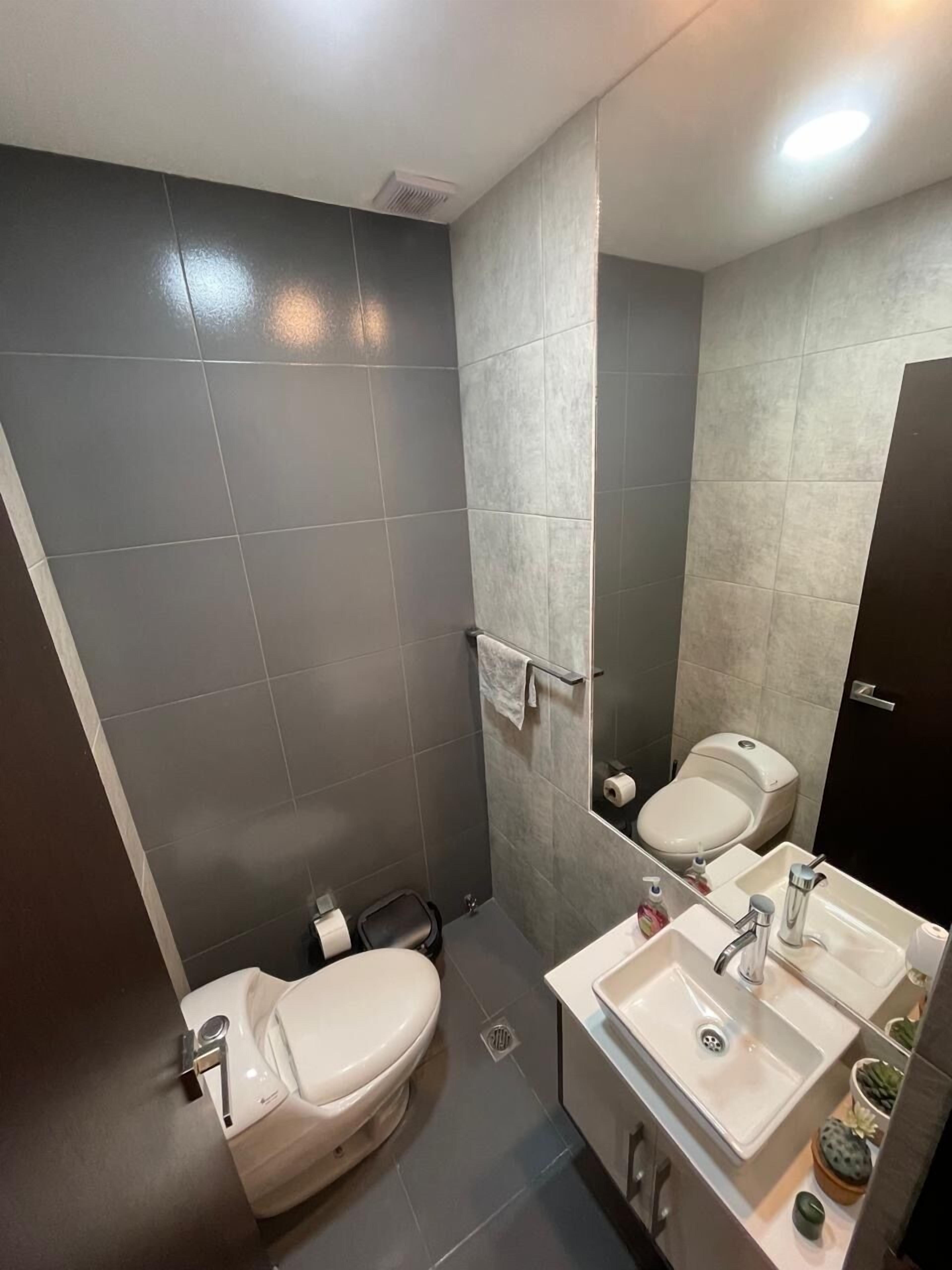 A modern bathroom with a toilet, sink, and mirror.