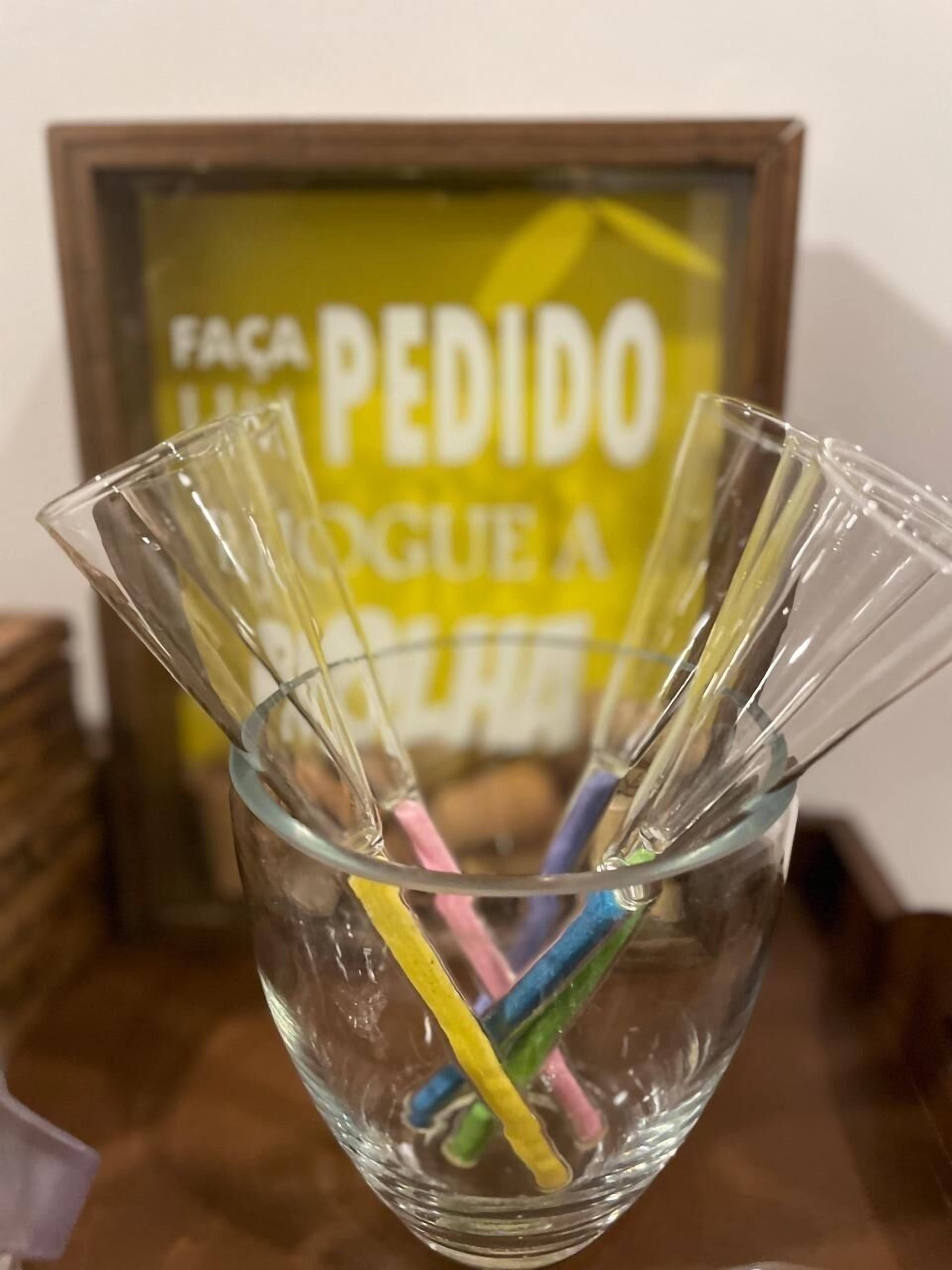 A clear glass bowl with colorful straws inside, placed on a table.