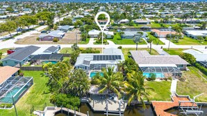 An aerial view of a residential area with houses, a swimming pool, and a marina. - Canalside 4BR villa with pool, spa, dock, and Gulf access. (Cape Coral)