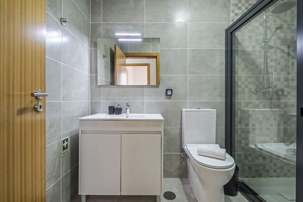 Un baño moderno con lavamanos blanco, inodoro y cabina de ducha de vidrio.