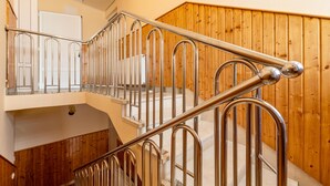 Un interior con varios niveles, una escalera de metal y paneles de madera.