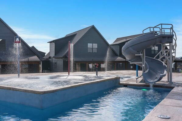 A swimming pool with a water slide and a fountain.
