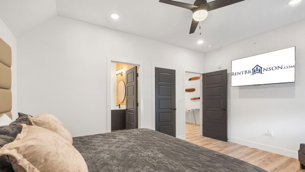 Un dormitorio moderno con una cama, un ventilador de techo y un televisor montado en la pared.