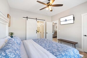 A bedroom with a bed, a ceiling fan, a sliding door, a bench, and a wall-mounted sign. - Table Rock Views with Private Hot Tub, Indoor/Outdoor Pools, Near Silver Dollar City & Free Tickets (Kimberling City)
