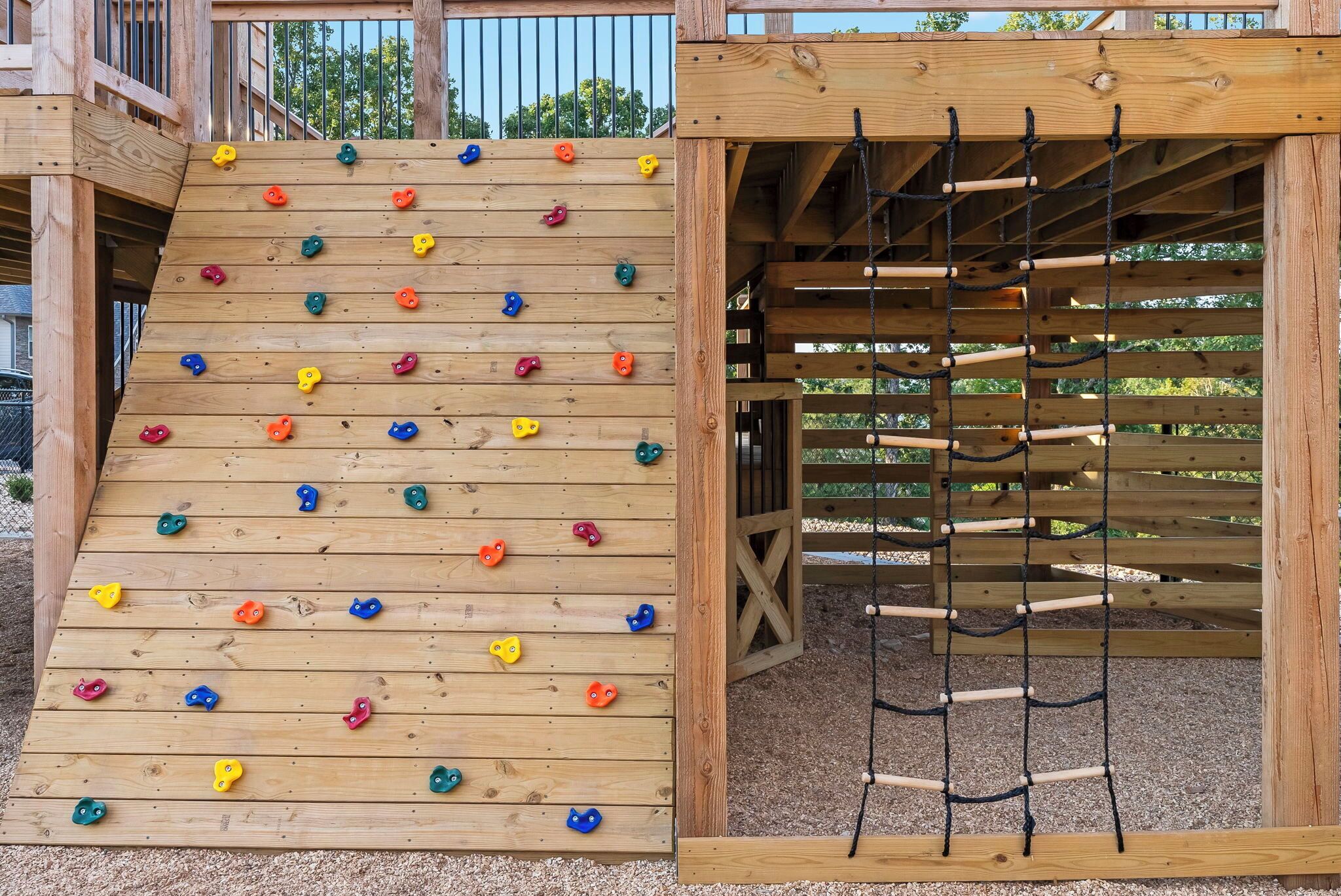 Une structure d’escalade en bois, dotée de prises colorées et d’une échelle en corde.