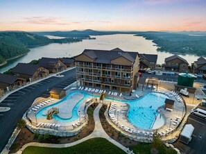 Ein Hotel mit großem Schwimmbad, Parkplatz und Blick auf einen Fluss.