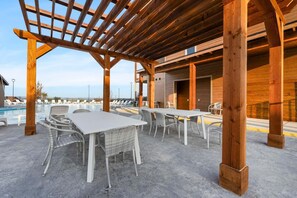 Eine Außenpatio-Terrasse mit Tischen, Stühlen, einem Pool und einer Holz-Pergola.