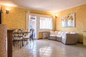 A living area with a dining table, chairs, a sofa, a wall-mounted painting, and a door leading outside. - Splendid 93 sqm apartment on two levels, ideal for 6 people, located on the ground floor of a building WITHOUT a lift (stairs to access it). The accommodation is located in an exclusive area in Porto Cervo, a few steps from the center and the characteris (Porto Cervo)