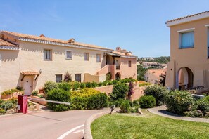 A residential area with stucco buildings, a paved road, and well-maintained greenery. - Splendid 93 sqm apartment on two levels, ideal for 6 people, located on the ground floor of a building WITHOUT a lift (stairs to access it). The accommodation is located in an exclusive area in Porto Cervo, a few steps from the center and the characteris (Porto Cervo)