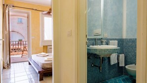 Una camera da letto con un letto, un bagno con lavandino e specchio, e un balcone con una sedia.