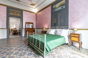 A bedroom with a bed, a nightstand, a dresser, a mirror, and a door leading to another room. - GuestHost - La Dimora dei Mille - Roomy Apartment with Terrace (Palermo)
