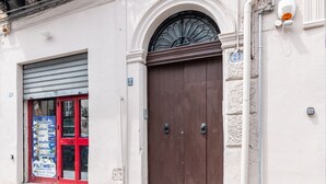 Un edificio con una puerta marrón cerrada, una ventana con marco rojo y un cartel con diversos servicios.