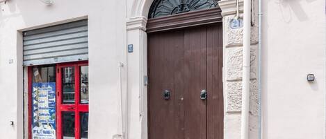 Un bâtiment avec une porte marron fermée, une fenêtre à cadre rouge et une enseigne indiquant différents services.