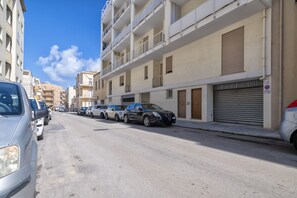 Eine Straße mit parkenden Autos, mehrstöckigen Gebäuden und blauem Himmel.