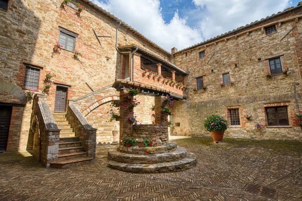 A courtyard with stone buildings, a central staircase, and flower boxes.