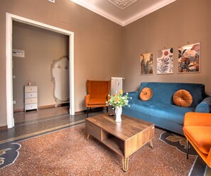 A room with a blue sofa, orange armchairs, a wooden coffee table with a vase, and artwork on the wall. - Appartamento Dalì, perfect for regenerating in Rapallo (Rapallo)