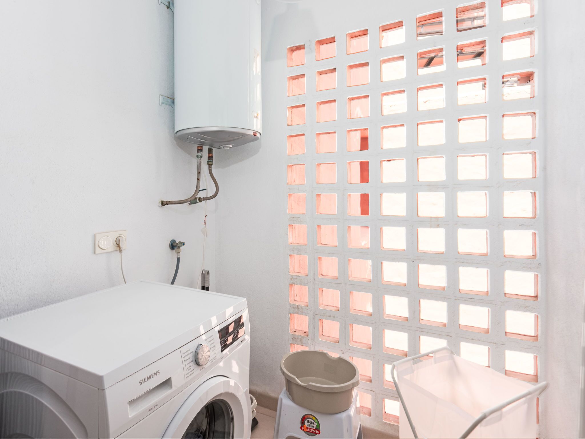 A laundry room with a white washing machine, a water heater, and a plastic container.