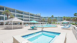 Un espace piscine comprenant des chaises longues, un belvédère et un bâtiment à plusieurs étages doté de balcons.