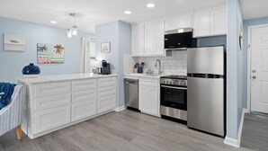 A modern kitchen with white cabinets, stainless steel appliances, and light blue walls.
