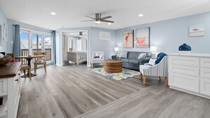 A spacious living area with a dining table, a sofa, and a large window.