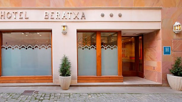 L’extérieur de l’hôtel Beratxa se distingue par sa façade moderne, ses grandes fenêtres et les plantes en pot qui décorent l’entrée.